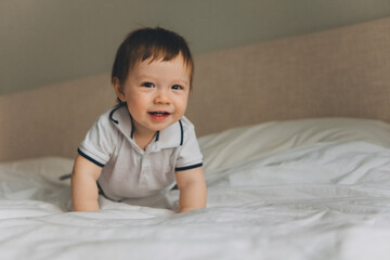 portrait of a smiling baby of one year on the bed at home