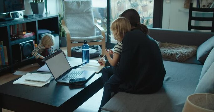 Freelance woman work at home using computer and care of children