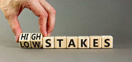 High or low stakes symbol. Concept words High stakes and Low stakes on wooden cubes. Businessman hand. Beautiful grey table grey background. Business high or low stakes concept. Copy space.