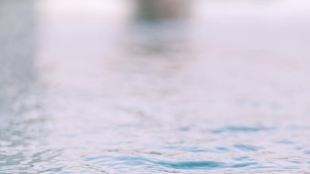 Woman enjoying hot thermal water in cold weather. Relaxing bath in outdoor whirl pool in wellness spa. Selective focus on water in front, unrecognizable person.