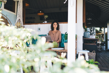 Contemplative female freelancer with digital netbook device thoughtful looking away thinking about...