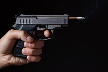 Concept of harm to smoking, smoking kills, A gun shooting a cigarette on a black background