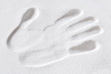 Handprint in the white sand of a beach