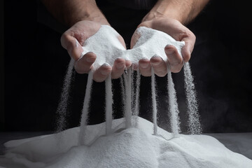 Men's hands keep sand in their palms and spilling grains of sand through their fingers. Concept of...