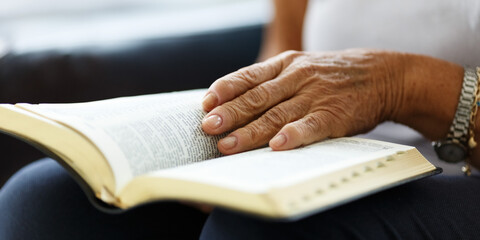 Closeup of senior woman's hands on bible, folded in prayer