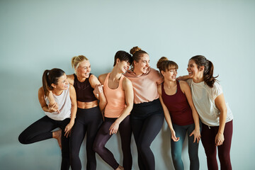 Laughing friends standing by a gym wall after yoga class