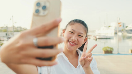 Young woman taking selfie on mobile phone on seascape background