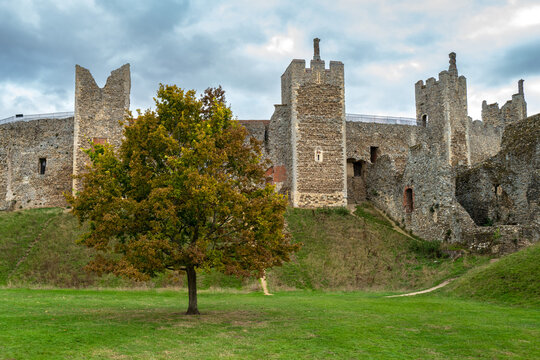 Dramatic view of part of a medieval castle showing its detailed stonework structure. A slope leads to a single tree in the moat area.castle,architecture,history,medieval,fortress,ancient,old,famous pl