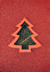 Fototapeta na wymiar Christmas tree card with red cutout glitter paper and spruce branches bursting through. Holiday, Xmas spirit minimal background.