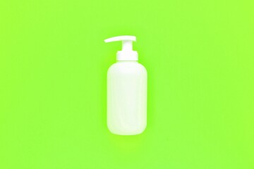White unbranded plastic dispenser pump bottle on light neon green background with copy space. Cosmetic package mockup, liquid soap flacon, hand sanitizer without label, shampoo organic spa, shower gel
