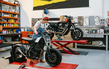 Photo sur Plexiglas Moto Mechanic woman placing custom motorcycle over platform on factory