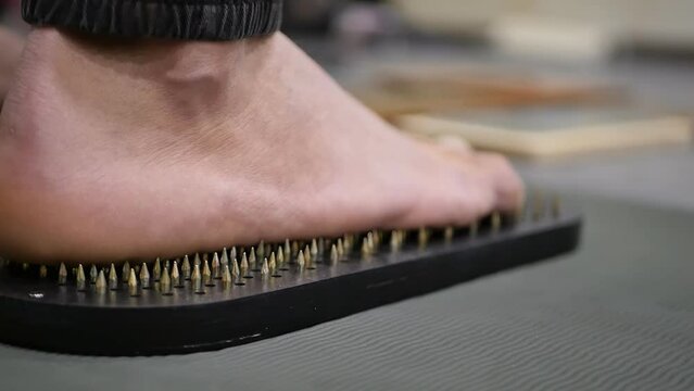 close-up men's feet have stepped on the Sadhu's board with sharp nails and stand in pain. The practice of standing on nails originated in India. Rishi board. Alternative medicine