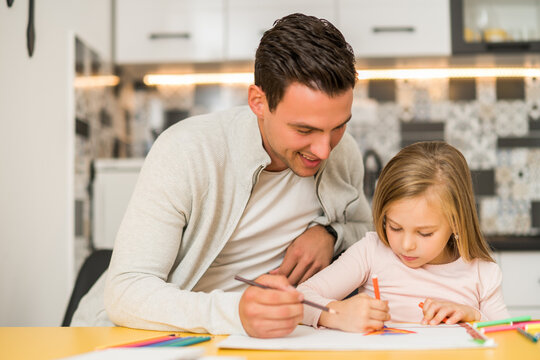 Little girl and her father enjoy drawing together at their home.	