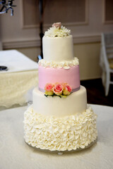 white pink wedding cake with roses on a table