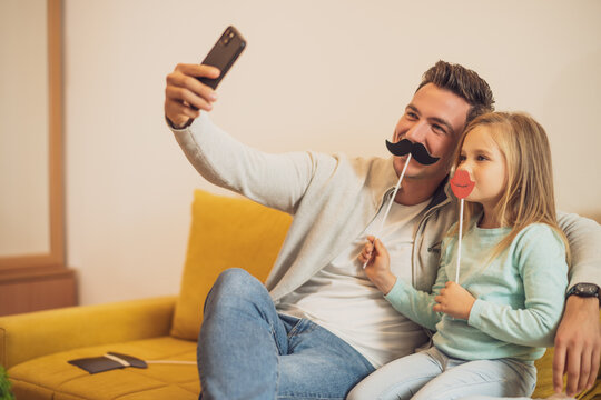 Father And Daughter Taking Selfie While They  Having Fun With  Party Props At Their Home.