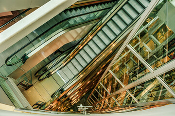 empty escalators and glass elevator, top down view - Powered by Adobe