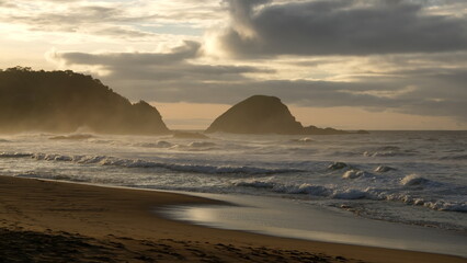 Fototapeta na wymiar Sunrise casting a golden glow over an islet and the beach in Zipolite, Mexico