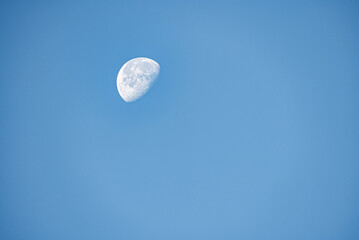 Close up of moon in the morning time with blue sky background, clear morning sky with bright growing moon in London.