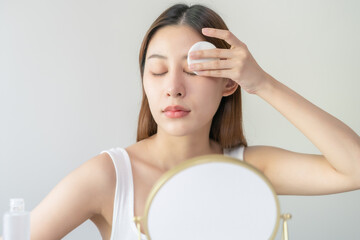 Relax beauty, attractive asian young woman, girl close eyes looking in mirror, hand holding cotton pad, apply facial wipe on her face remover makeup, essence or lotion for treatment, skin care routine - obrazy, fototapety, plakaty