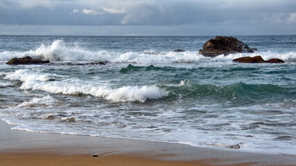 Waves breaking on the beach, with a rock just offshore, in Zipolite, Mexico