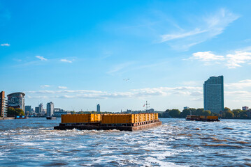 London, England. May 7, 2022. Industrial barge passing business center in London on the River...
