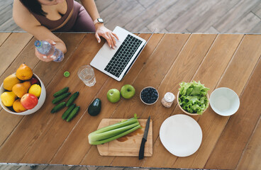 Woman with bottle of water using laptop