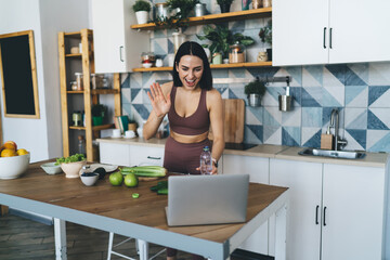 Woman having video conversation on laptop while preparing healthy breakfast