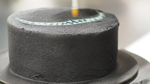 chef pastry cook spraying and preparing a black frosted cake for birthday