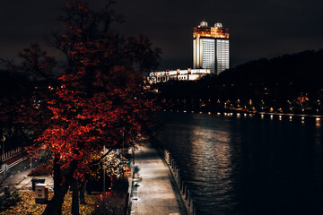 Night city landscape of tree with red foliage, river and Russian Academy of Sciences building in Moscow