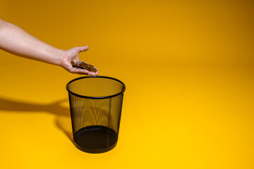 A man throws a handful of copper coins into a trash can. The concept of poverty and savings