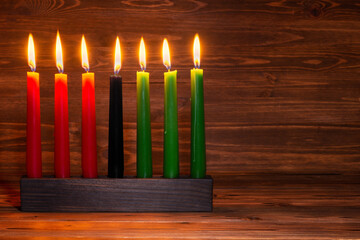 Kwanzaa festival concept with seven candles red, black and green in candlestick on wooden background, copy space