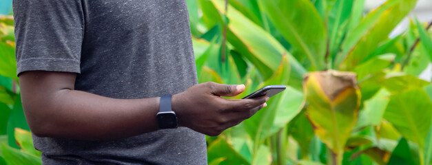 Hand of an African farmer man holding a black smartphone.