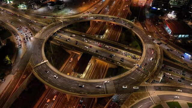 Aerial drone time lapse night video of illuminated multi level ring highway road passing through busy city centre