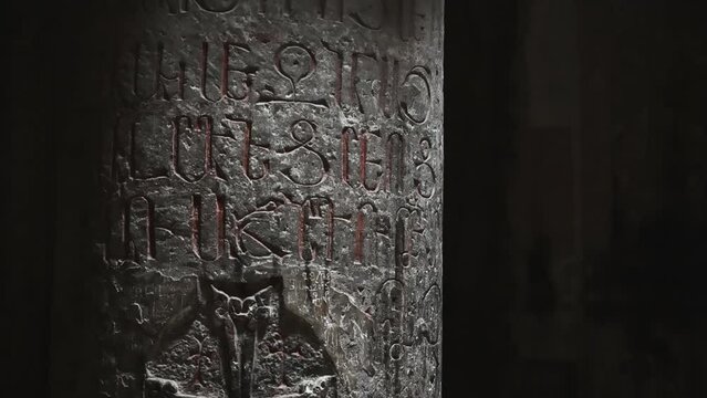 The columns of the ancient geghard monastery temple, illuminated through the windows, are carved with religious symbols on the walls.