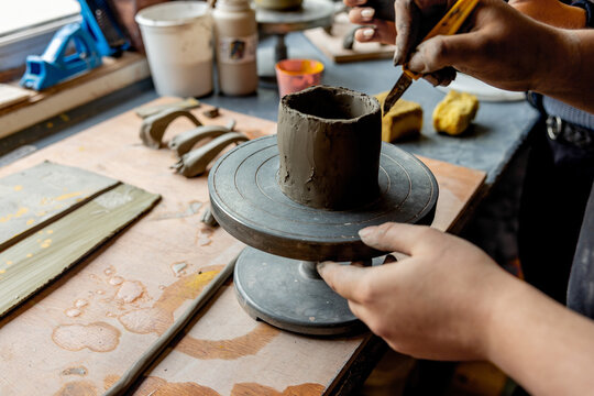 Hands Crafting Cup on a Pottery Wheel in Ceramic Studio
