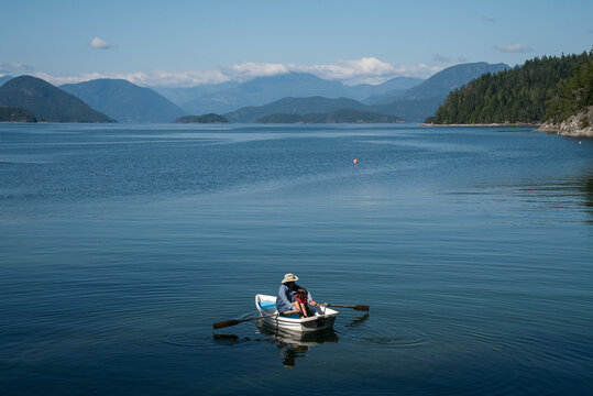 A grandfather and granddaughter in a small row boat in a large bay
