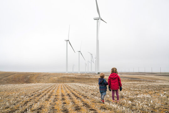 Two children stand looking at a line of giant windmills