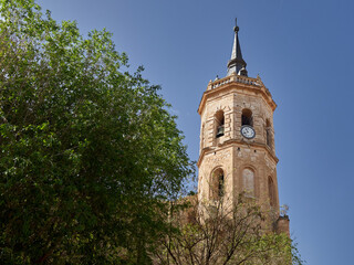 Fototapeta na wymiar Bell tower with a clock of the church of Nuestra Señora de la Asuncion. Tembleque, a village in the route of Don Quixote, province of Toledo, Castilla La Mancha, Spain, Europe
