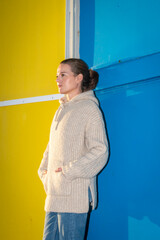 Mid adult attractive woman standing against a blue and yellow wall.