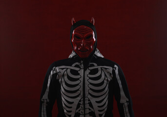 man in devil mask on red background