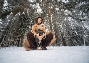 Obraz premium Portrait of a young beautiful girl with a Yorkshire terrier in the winter forest.