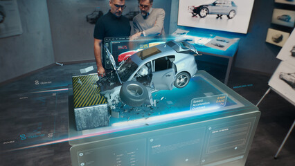 Two engineers Developers standing in design studio near futuristic holographic table and make a test in a 3d car crash test simulator, which simulates a road accident check the safety © Framestock