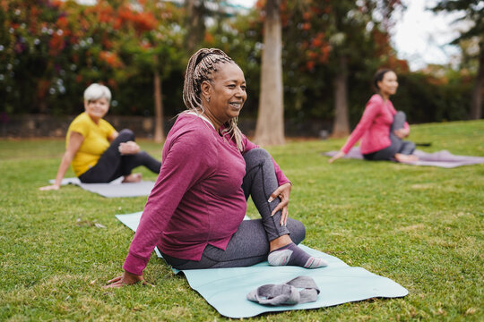 Multi generational women having fun doing yoga exercise at city park together - Focus on african senior woman