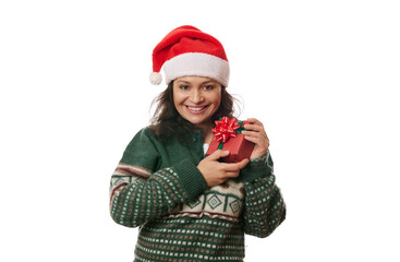 Attractive Hispanic woman in Santa hat and warm wool green sweater, with Christmas present, sweetly smiling looking at camera, isolated on white background. Winter events. Boxing Day. Christmastime