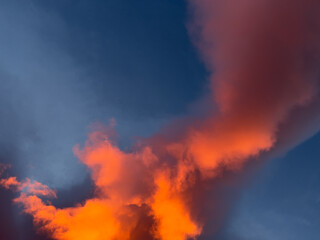 Sunrise  overhead  looks like bright orange fire in the dark blue sky. Clouds are large and swirling.