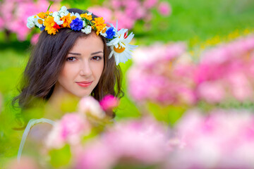 Fairy tale image art photo. Outdoor close up portrait of young beautiful happy smiling fantasy woman. Young goddess enjoys spring nature in bright sunlight and many pink roses