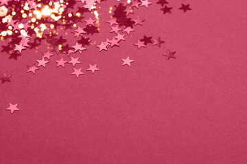 Beautiful festive magenta background with metallic star shaped confetti. Christmas holidays background. Copy space for your text. Color trend year 2023.