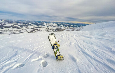 The snowboard stands in the snow high up in the snowy mountains. Sunny weather. ski resort
