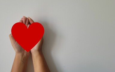 female hand holding a red heart