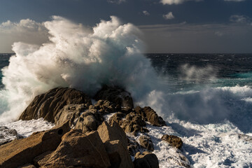 The huge waves of the stormy sea explode on the seashore cliffs